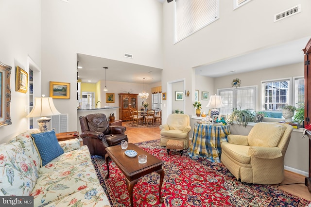 living room with a towering ceiling, hardwood / wood-style floors, and a chandelier