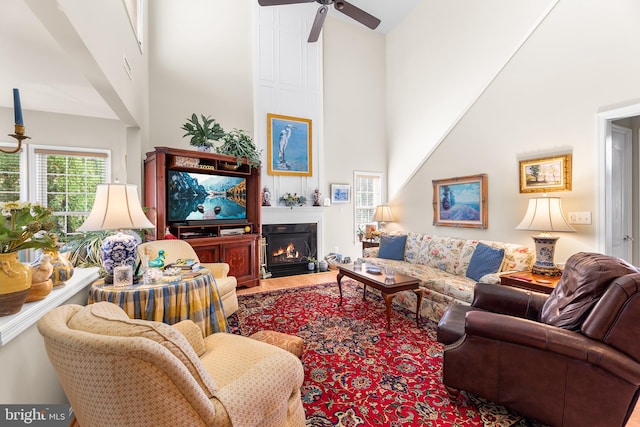 living room featuring wood-type flooring, a high ceiling, and ceiling fan