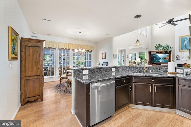 kitchen with light wood-type flooring, ceiling fan with notable chandelier, hanging light fixtures, and stainless steel dishwasher