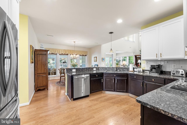 kitchen featuring decorative light fixtures, stainless steel appliances, white cabinetry, and a healthy amount of sunlight