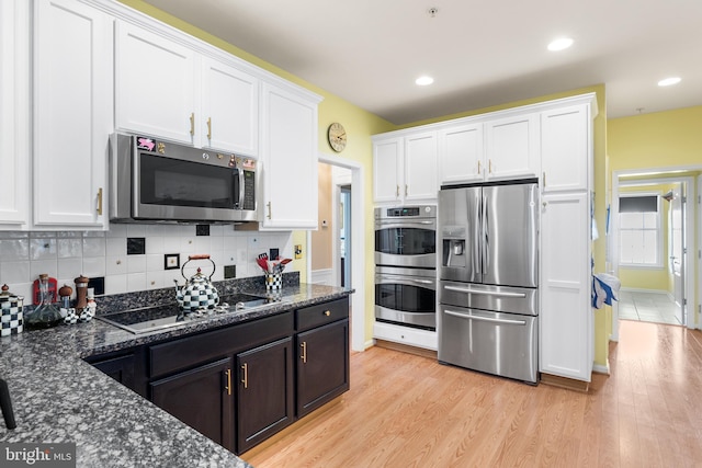 kitchen with light hardwood / wood-style floors, dark stone counters, stainless steel appliances, and white cabinets