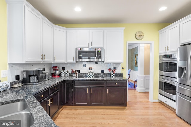 kitchen with appliances with stainless steel finishes, white cabinetry, tasteful backsplash, and light hardwood / wood-style flooring