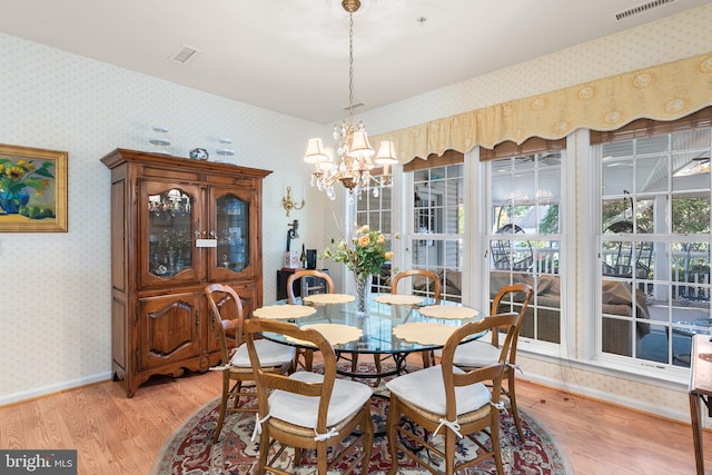 dining space with light hardwood / wood-style floors and a chandelier