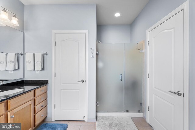 bathroom featuring tile patterned flooring, a shower with shower door, and vanity