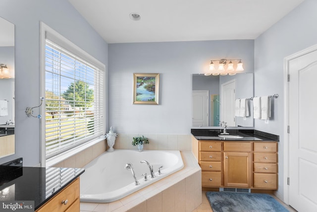 bathroom with tiled tub, tile patterned flooring, and vanity