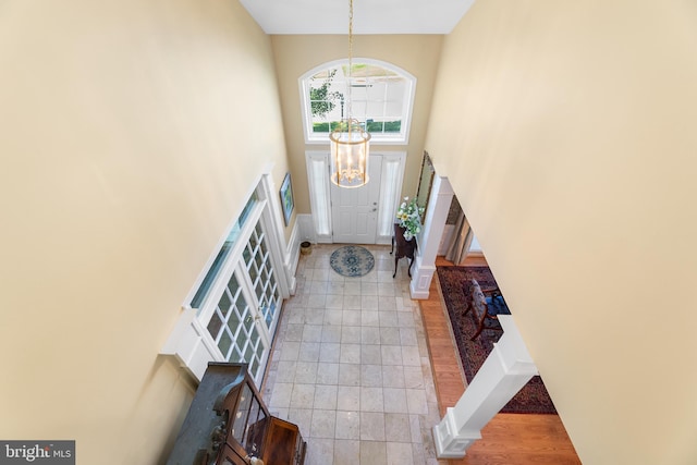 entryway with a notable chandelier, light hardwood / wood-style flooring, and a towering ceiling