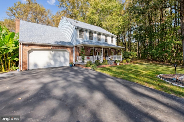 view of front of home featuring covered porch, a garage, and a front lawn