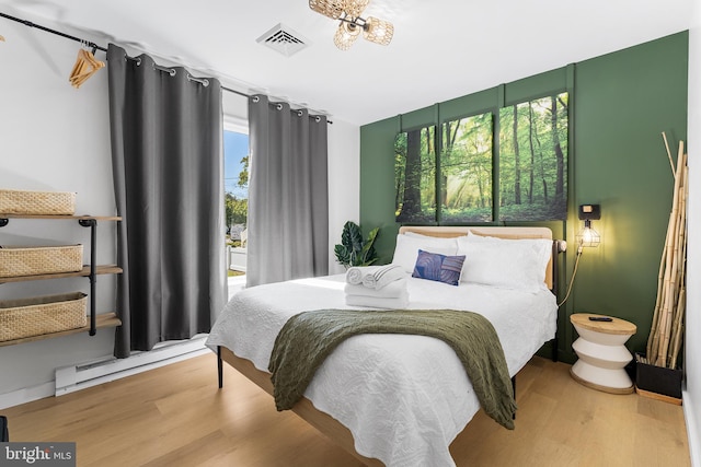 bedroom with wood-type flooring and a baseboard heating unit