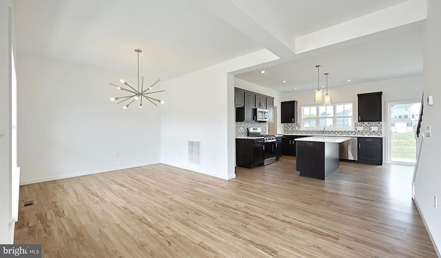 kitchen with a kitchen island, an inviting chandelier, light hardwood / wood-style flooring, appliances with stainless steel finishes, and backsplash