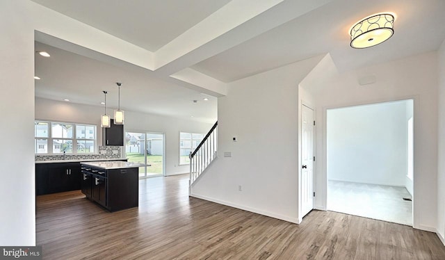 kitchen featuring hanging light fixtures, sink, light hardwood / wood-style flooring, backsplash, and a center island