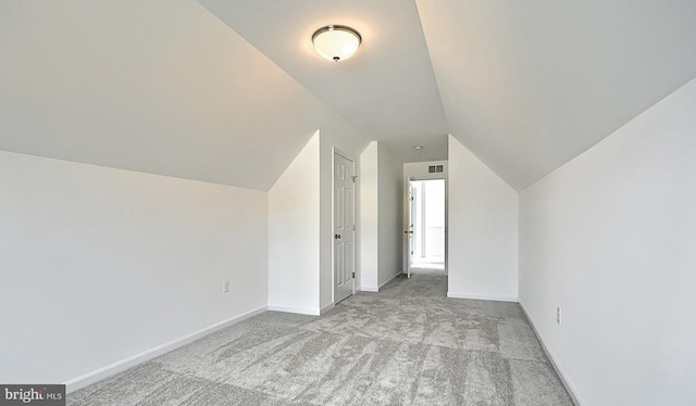 bonus room with vaulted ceiling and light colored carpet