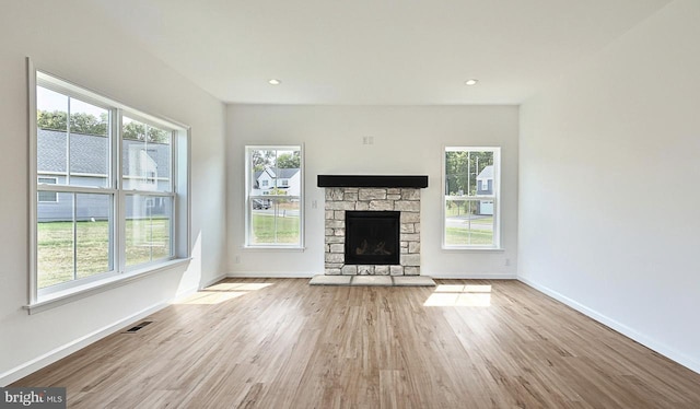 unfurnished living room with a fireplace, plenty of natural light, and light hardwood / wood-style floors