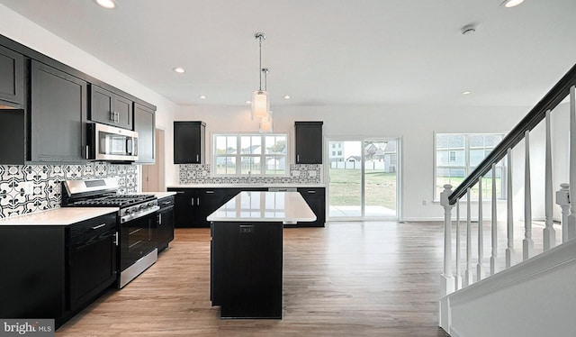 kitchen featuring a kitchen island, decorative light fixtures, light hardwood / wood-style flooring, stainless steel appliances, and decorative backsplash