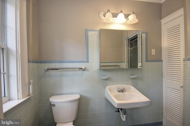 bathroom featuring toilet, tile walls, and sink