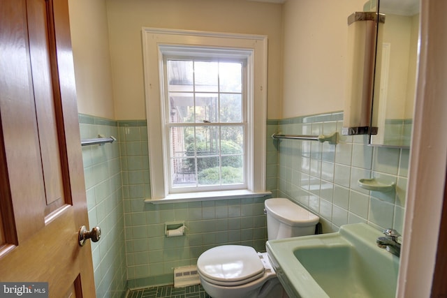 bathroom with toilet, sink, and tile walls