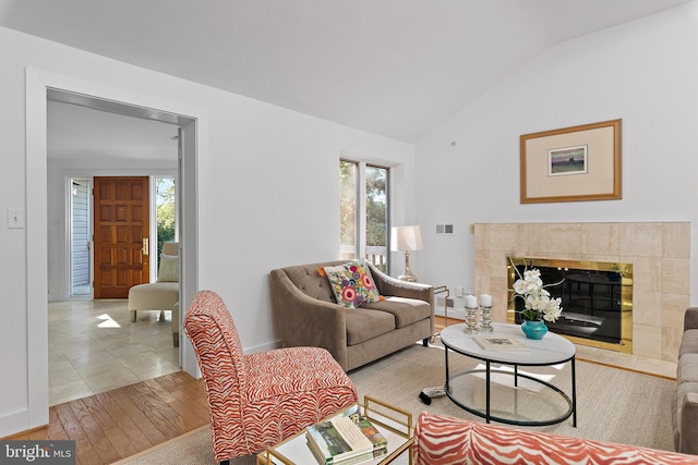 living room featuring light hardwood / wood-style flooring, lofted ceiling, and a tile fireplace