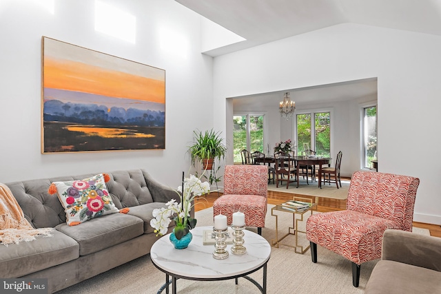 living room with hardwood / wood-style flooring, a notable chandelier, and lofted ceiling