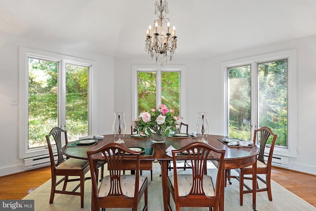 dining room with light hardwood / wood-style floors, an inviting chandelier, and baseboard heating