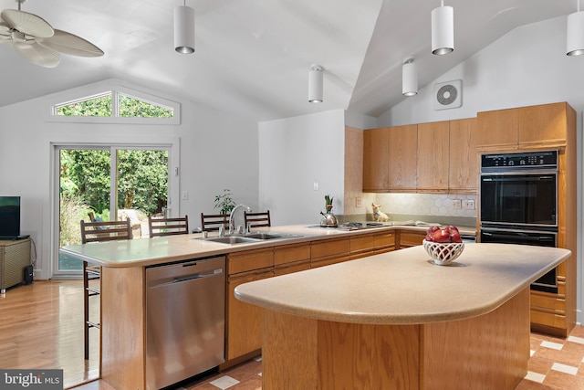 kitchen with lofted ceiling, a kitchen island, appliances with stainless steel finishes, sink, and decorative light fixtures