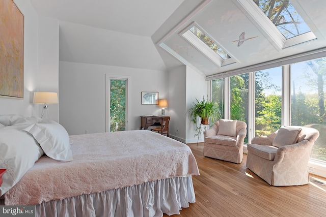 bedroom featuring lofted ceiling with skylight and hardwood / wood-style flooring