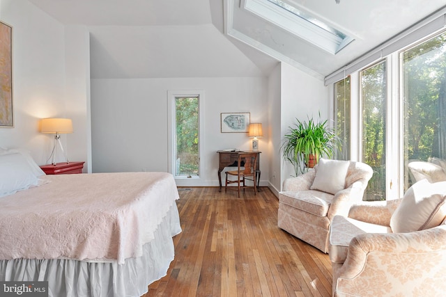 bedroom featuring vaulted ceiling with skylight, multiple windows, and hardwood / wood-style flooring