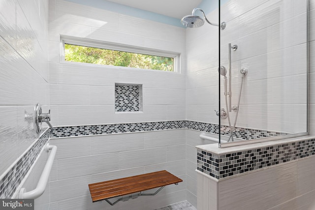 bathroom with a tile shower and tile walls