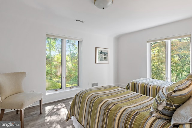 bedroom with hardwood / wood-style floors and multiple windows