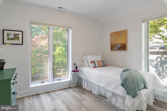 bedroom with multiple windows and light wood-type flooring