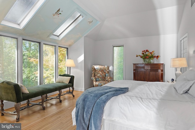 bedroom with lofted ceiling with skylight, multiple windows, and light wood-type flooring