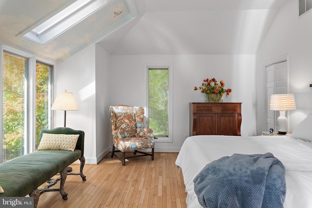 bedroom with lofted ceiling with skylight and light wood-type flooring