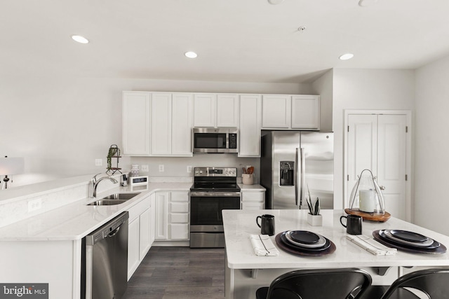 kitchen featuring light stone countertops, white cabinets, appliances with stainless steel finishes, and dark hardwood / wood-style flooring