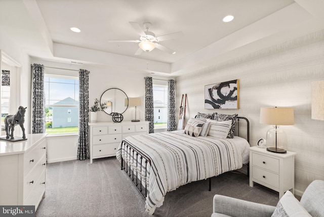 bedroom with ceiling fan, carpet floors, and a tray ceiling