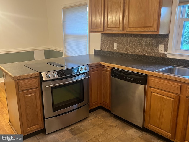 kitchen with kitchen peninsula, tasteful backsplash, stainless steel appliances, and sink