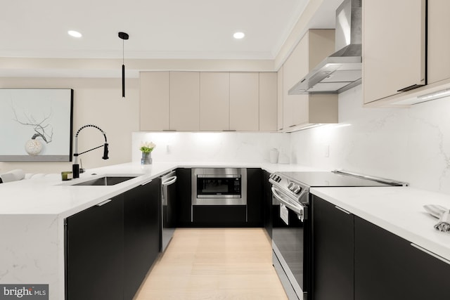 kitchen with wall chimney range hood, backsplash, sink, stainless steel appliances, and hanging light fixtures