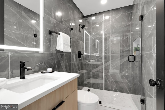 bathroom featuring tile walls, a shower with shower door, vanity, and toilet