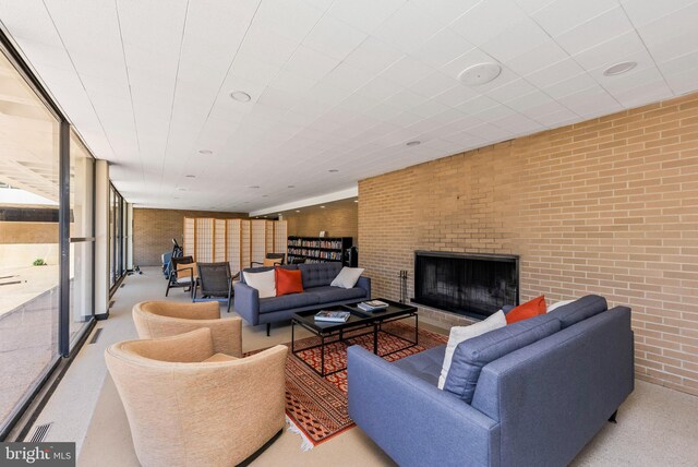 carpeted living room featuring brick wall and expansive windows