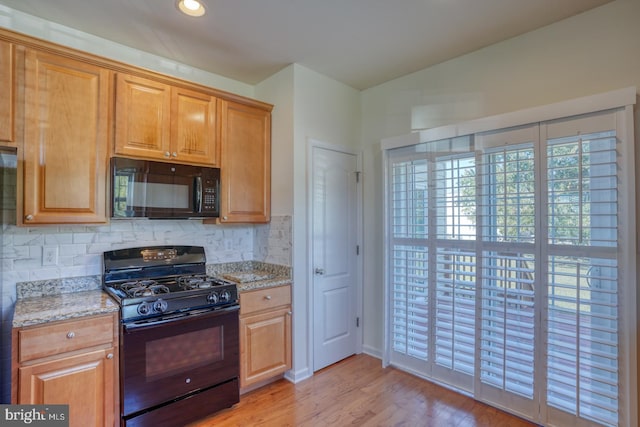 kitchen featuring black appliances, decorative backsplash, light stone countertops, and light hardwood / wood-style flooring