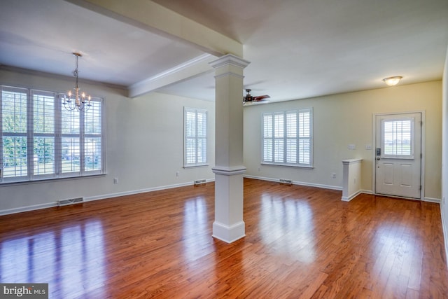 unfurnished living room featuring beam ceiling, hardwood / wood-style flooring, ceiling fan with notable chandelier, crown molding, and ornate columns