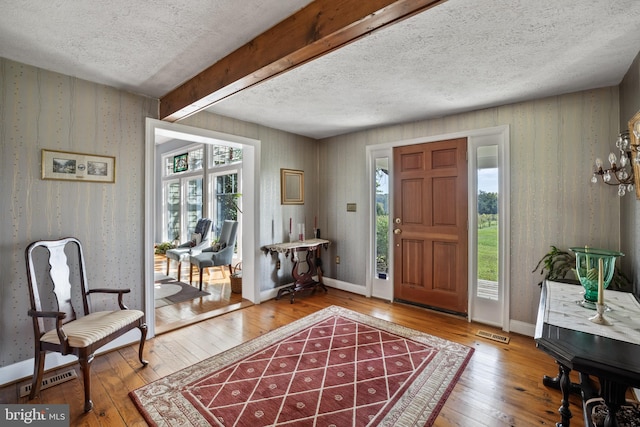 entryway featuring beam ceiling, hardwood / wood-style flooring, a wealth of natural light, and a textured ceiling