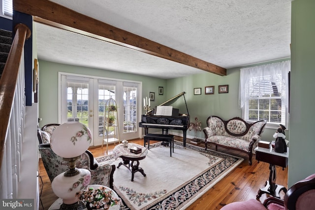 living room with french doors, beam ceiling, hardwood / wood-style flooring, and a textured ceiling