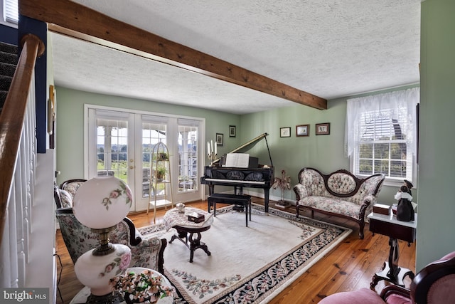 living area with a textured ceiling, french doors, wood-type flooring, and beam ceiling