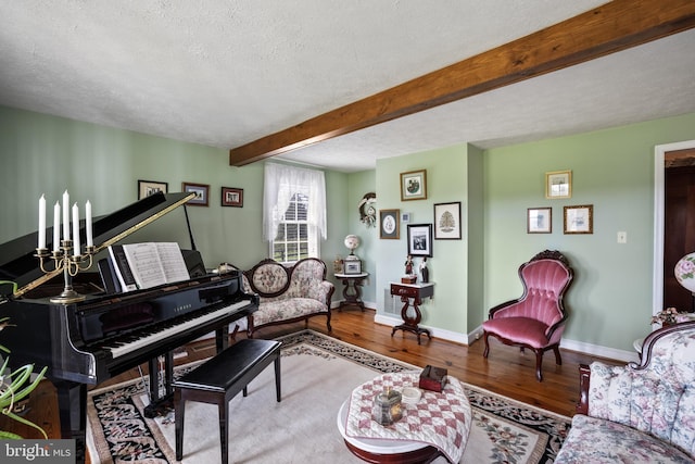 sitting room with beam ceiling, baseboards, wood finished floors, and a textured ceiling