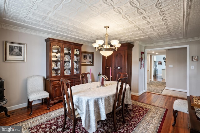 dining area featuring an ornate ceiling, baseboards, a notable chandelier, and wood finished floors