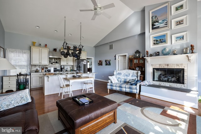 living room with dark wood-type flooring, high vaulted ceiling, and ceiling fan