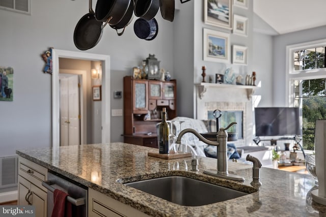 kitchen featuring a sink, visible vents, stainless steel dishwasher, and dark stone countertops