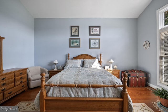 bedroom with dark wood-style flooring and vaulted ceiling