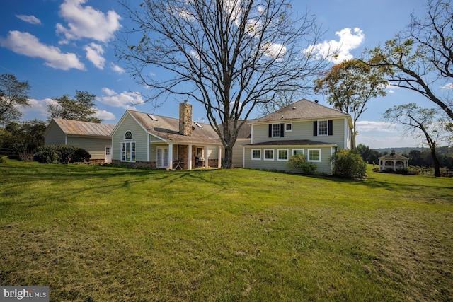 rear view of house with a chimney and a yard