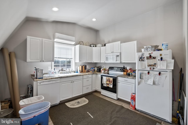 kitchen with white cabinets, lofted ceiling, white appliances, light stone countertops, and a wall mounted air conditioner