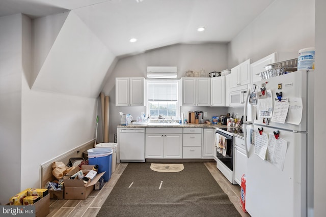 kitchen featuring white appliances, lofted ceiling, a wall mounted AC, hardwood / wood-style flooring, and white cabinetry