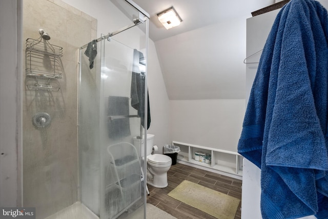 bathroom featuring lofted ceiling, walk in shower, hardwood / wood-style flooring, and toilet